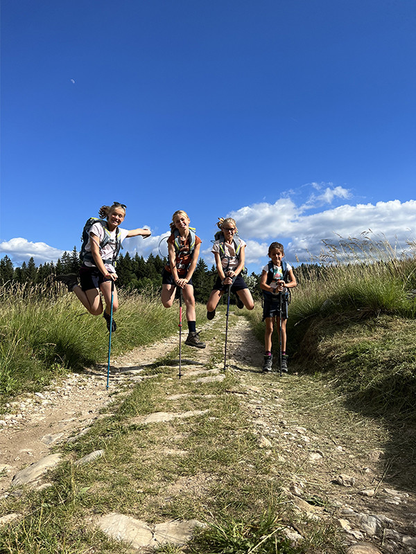 4 randonneurs sur une piste dans une prairie sautant en l'air