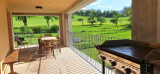 Grande terrasse ensoleillée avec table de repas et barbecue